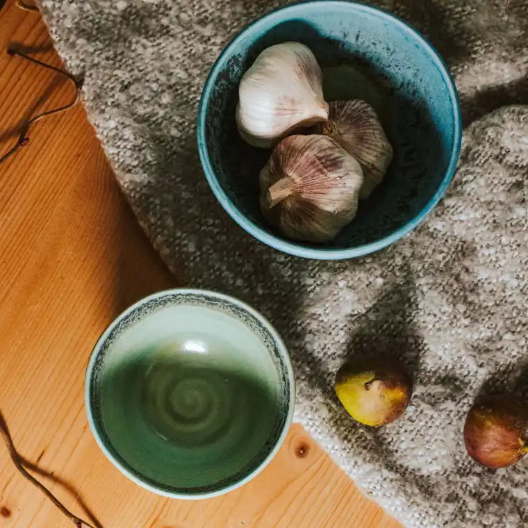 Ceramic bowls with garlic bulbs and pears on a table