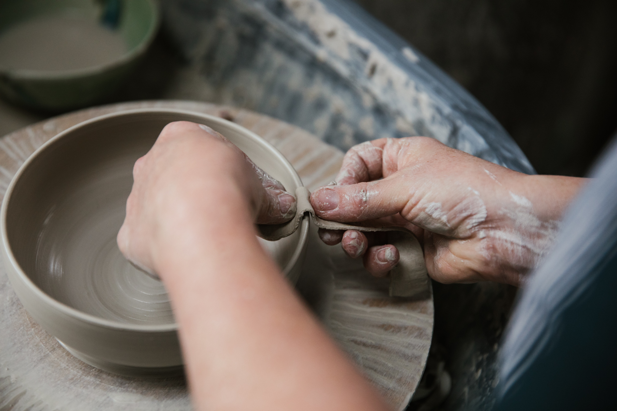 Lorna Gilbert sitting at her wheel throwing a bowl in white stoneware clay