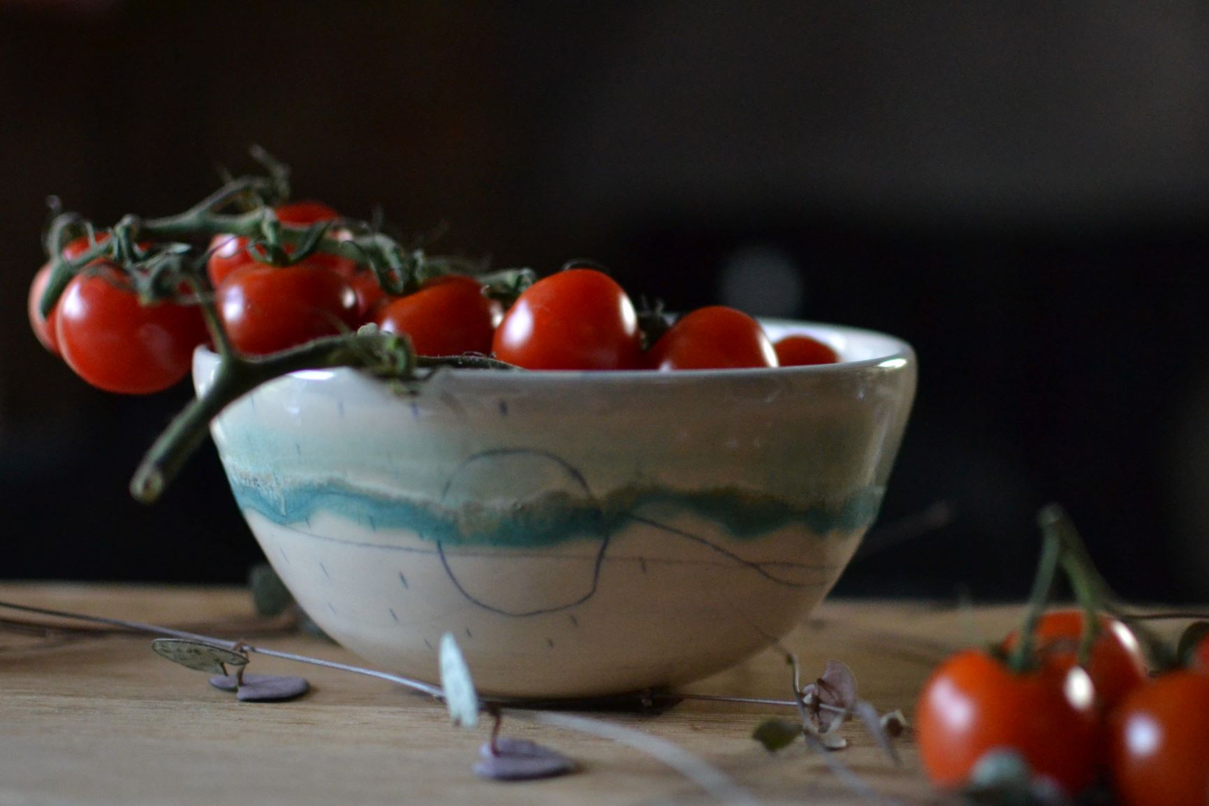 A handmade ceramic tapas bowl full to the brim with tomatoes on the vine.