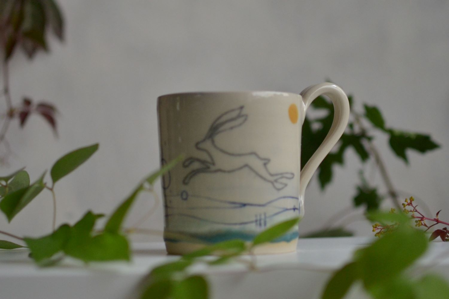 Handmade ceramic mug with a hare running across it.